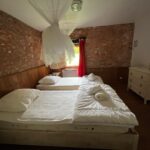 Chambre d'hôtel avec deux lits, rideaux blancs, meuble de rangement blanc, Zanni Compagnie.