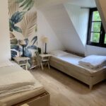 Chambre avec deux lits, mur tropical, fenêtre, lampe, Zanni Compagnie.