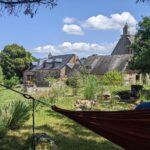 Personne dans un hamac devant des bâtiments anciens.